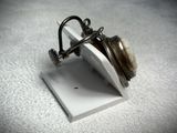 a silver pocket watch on a stand on a white surface