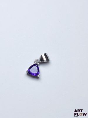 un gros plan d'un pendentif violet en forme de cœur posé sur une surface blanche