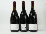 trois bouteilles de vin rouge sont alignées sur une surface blanche