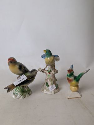 three small figurines of birds are sitting on a white surface