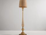 un lampadaire doré surmonté d'un abat-jour beige