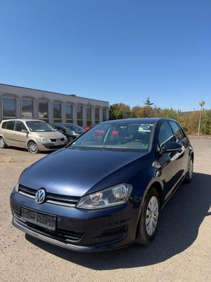 une Volkswagen Golf bleue garée sur un parking à côté d'un immeuble