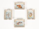quatre assiettes carrées ornées de poissons et de coquillages, posées sur un fond blanc