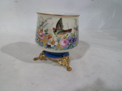 un petit vase avec un oiseau sur un support