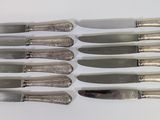 six knives are lined up in a row on a white surface