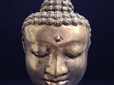 a silver statue of a buddha head on a black background