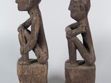 pair of wooden figures of a man and a woman sitting on blocks