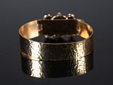 an image of a close up of a gold bracelet on a black surface