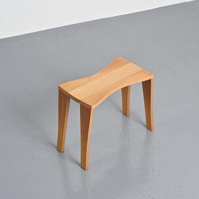 un petit banc en bois posé à même le sol dans une pièce