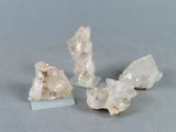 trois morceaux de quartz posés sur un socle en verre, sur une surface grise