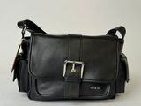 un sac à bandoulière en cuir noir orné d'une boucle métallique sur le devant
