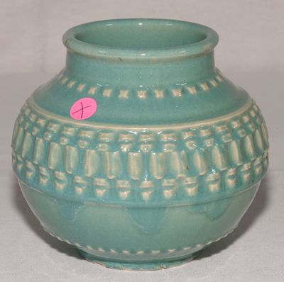 un vase vert sur lequel est collé un autocollant rose