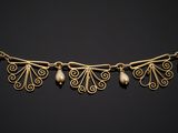 a gold necklace with pearls on a black background