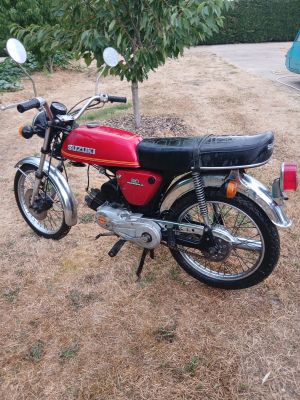 une moto rouge garée dans une cour, près d'un arbre
