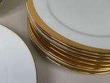 several white plates with gold rims stacked on top of each other