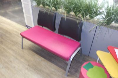 un banc rose avec deux chaises noires à côté d'une jardinière