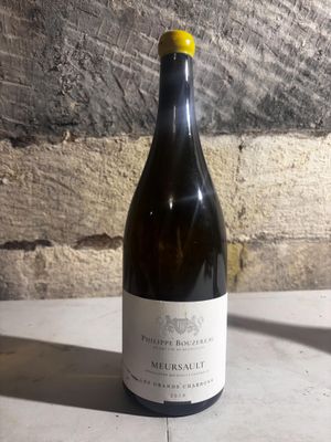 a bottle of wine sitting on a table next to a brick wall
