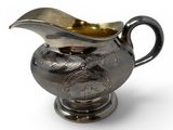 a silver pitcher with a bird on it on a white surface