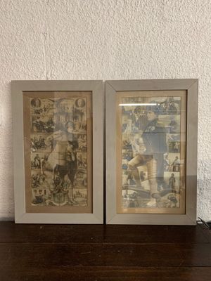 two framed pictures on a wooden table with a lamp