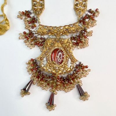 un collier en or orné d'un motif rouge et blanc