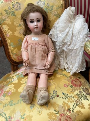une poupée assise sur une chaise, vêtue d'une robe