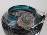 a black bowl with a green lid sitting on a table