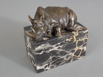 statue of a rhino resting on a marble block on a gray surface