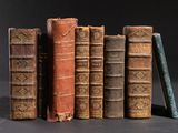 several old books are stacked on top of each other on a table