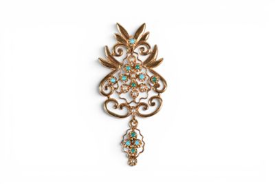 un gros plan d'une broche en or et turquoise sur fond blanc