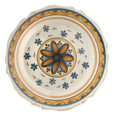 a plate with a flower design on it on a white surface