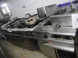 une cuisine équipée d'une cuisinière, d'un évier et d'une casserole posée sur le plan de travail