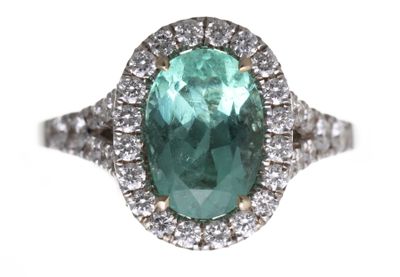 gros plan d'une bague avec une pierre verte entourée de diamants blancs