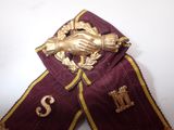 a purple and gold ribbon with a gold hand on it