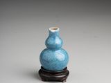an image of a small blue vase sitting on top of a wooden stand