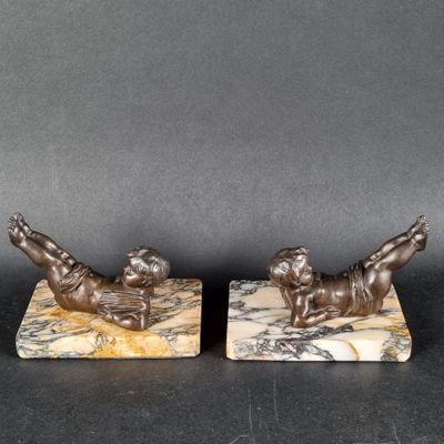 une paire de figurines en bronze représentant un garçon et une fille, posées sur des socles en marbre