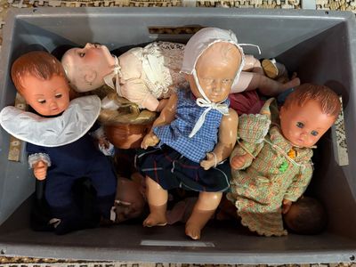 beaucoup de poupées dans une boîte posée par terre