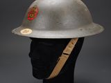 a silver helmet on a manne head with a red badge on it