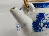a blue and white tea pot with chopsticks in it
