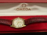une photo d'une montre en or dans un coffret rouge posé sur une table