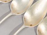 three silver spoons are lined up in a row on a table