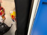a black trash can sitting next to a blue door