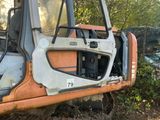 un camion rouillé, orange et blanc, garé dans les bois