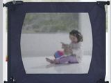 a little girl that is sitting in front of a baby gate