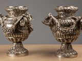 two silver vases sitting on top of a table next to each other