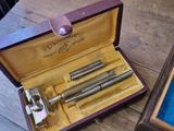 a wooden box with a razor and other items in it on a table
