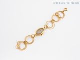 a close up of a gold bracelet with a stone in the middle