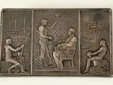 une plaque métallique sur laquelle figurent une femme et deux hommes