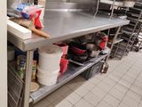 une cuisine avec un plan de travail en inox sur lequel sont posés de nombreux plats et casseroles