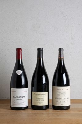 trois bouteilles de vin sont alignées sur une table en bois