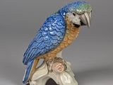 une figurine représentant un oiseau bleu et jaune perché sur une branche